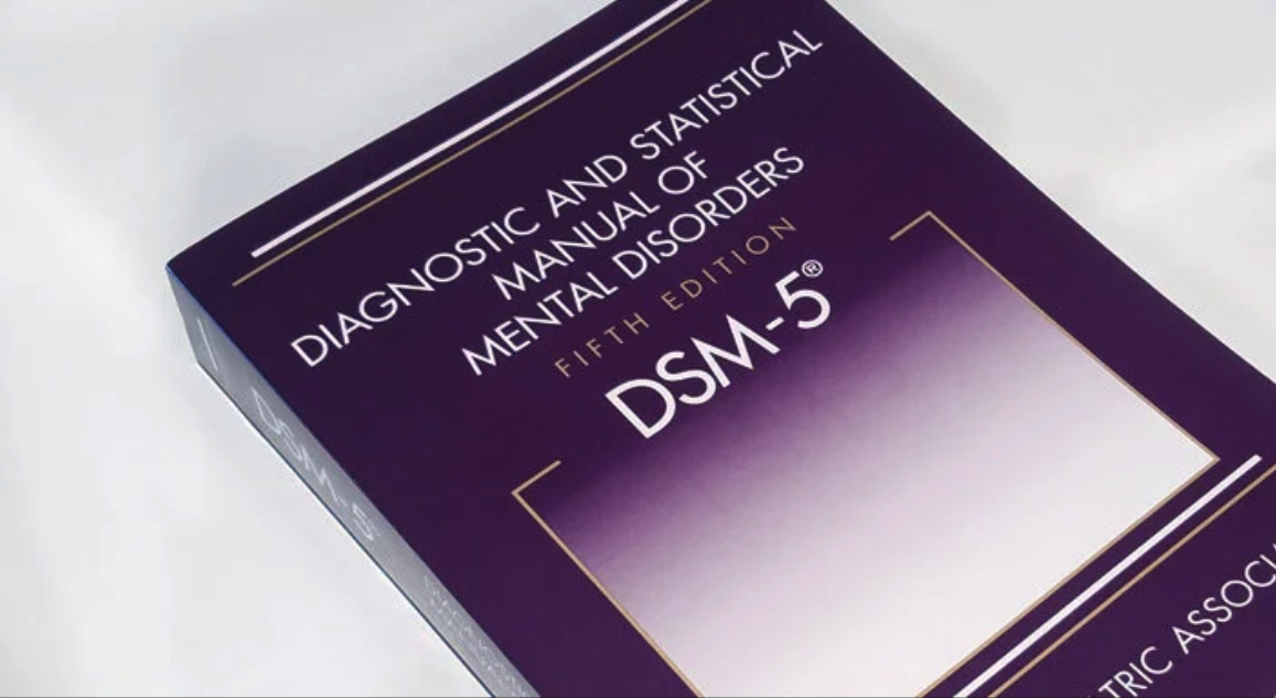 Image of a large purple and white book, the DSM-5