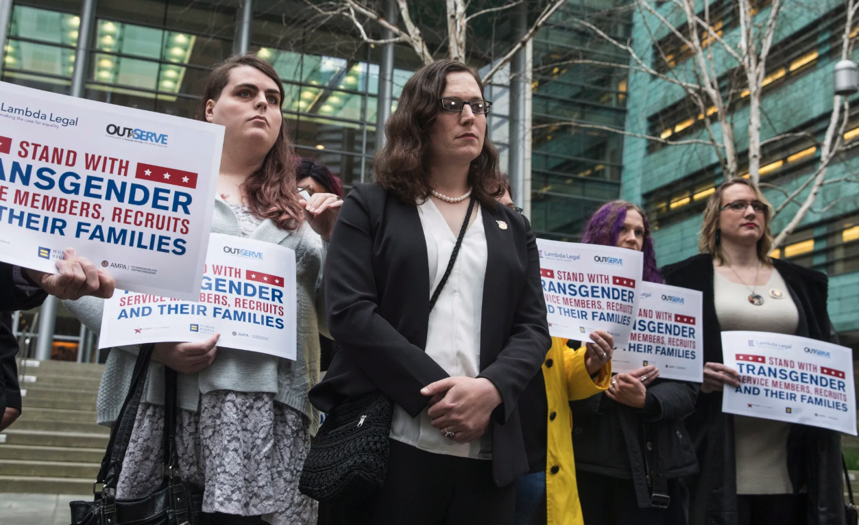 In this March 27, 2018 photo, plaintiff U.S. Army Ssgt. Katie Schmid, center, listens to a speaker during a news conference following oral arguments in a case to block a transgender military ban at the U.S. Western District Federal Courthouse in Seattle. Stephen Brashear/AP Images for Human Rights Campaign